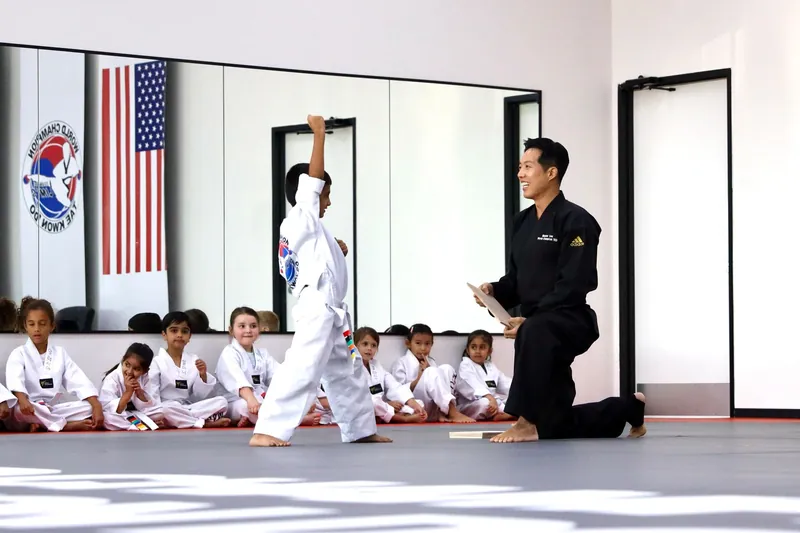A student breaking a board held by an instructor while the class watches