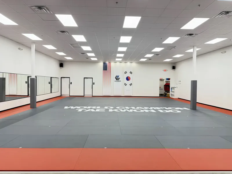 The training floor at Leaders Taekwondo Cypress, with World Champion Taekwondo on the mats and the flags on the far wall