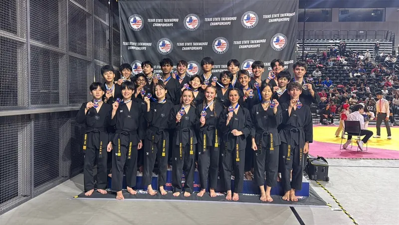 The Leaders Taekwondo Demo Team with their medals in front of the Texas State Taekwondo Championships backdrop
