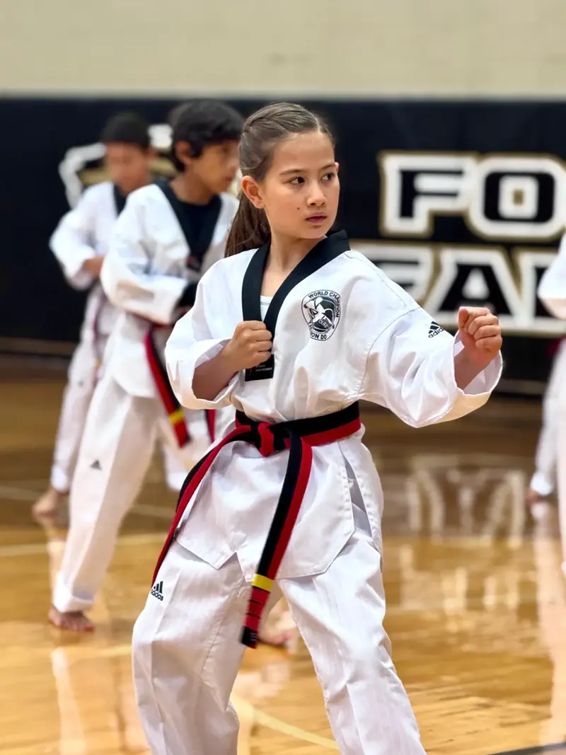 A student in a red and black belt in a fighting stance