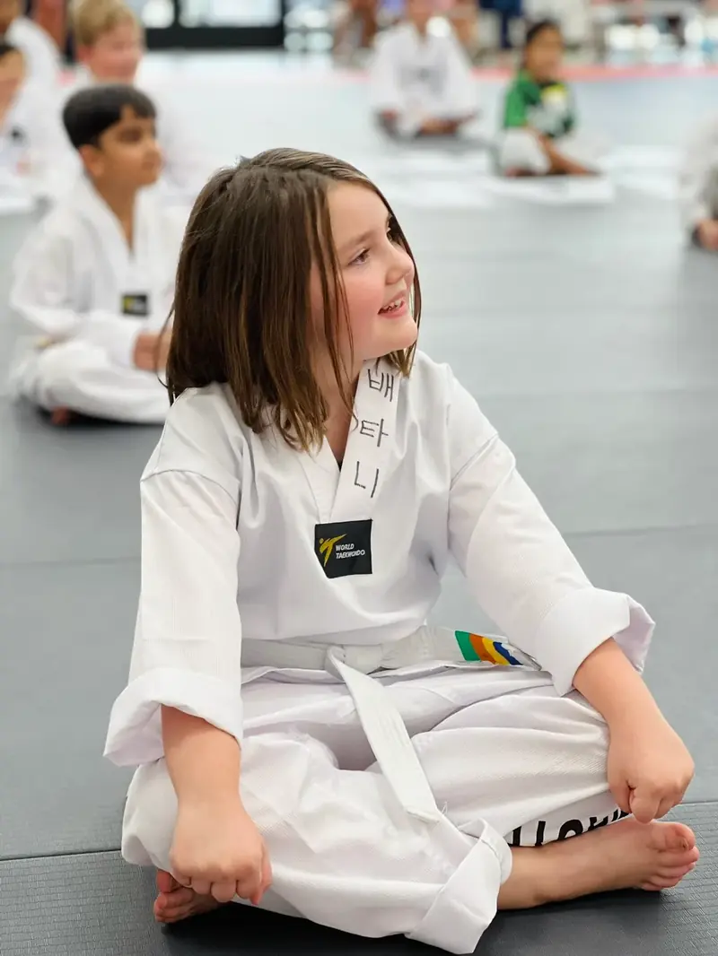 A student in uniform sitting on the mat