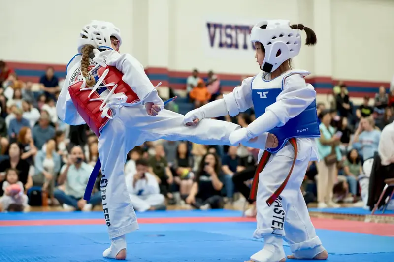 Two students sparring in protective gear at a tournament